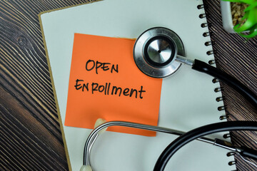 Concept of Open Enrollment write on sticky notes with stathoscope isolated on Wooden Table.