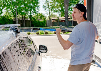 A man washing a car at a self-service car wash