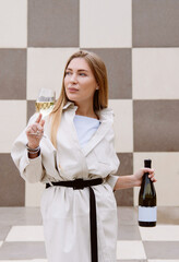 young woman tasting white wine against chessboard background