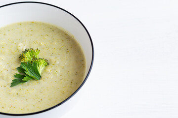 close-up green Broccoli cream soup on white background with copy space. Fresh broccoli soup in a bowl healthy eating. vegetable soup with crackers.