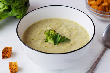 Fresh broccoli soup in a bowl with bread healthy eating. green Broccoli cream soup on white background with copy space. vegetable soup with crackers.