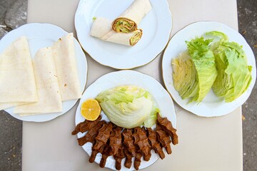 Delicious meat kebab with fresh vegetable salad served with variety of Turkish dishes and appetizers. Top view of assorted Turkish food and meze, tasty and healthy Mediterranean cuisine.