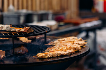 Cook grills kebab chicken open fire. Turns meat over with tongs. Concept Street food