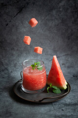 Mint, ripe watermelon, refreshing watermelon juice on a dark background.