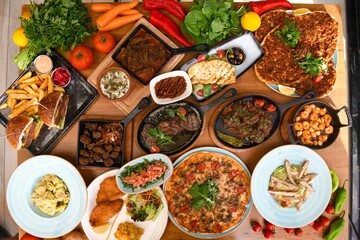 Delicious meat kebab with fresh vegetable salad served with variety of Turkish dishes and appetizers. Top view of assorted Turkish food and meze, tasty and healthy Mediterranean cuisine.