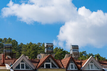 Tiled roof of a house with satellite dishes and tanks for heating water.