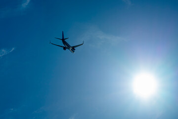 the plane is flying against a background of blue sky and sun