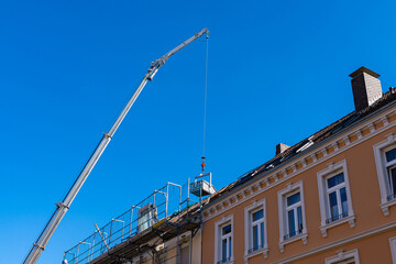 Fototapeta premium Crane boom over a residential building falling building material on the roof.