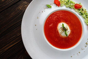 Tomato soup in a white plate on a wooden background