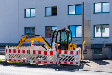Yellow excavator fenced with traffic barriers.