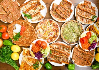 Traditional Turkish cuisine. Pizza, pita, pidesi, sucuk, hummus, kebab. Many dishes on the table. Serving dishes in restaurant. Background image. Top view, flat lay