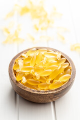 Fish oil capsules. Yellow omega 3 pills in bowl on white table.