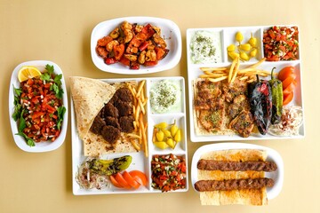 Delicious meat kebab with fresh vegetable salad served with variety of Turkish dishes and appetizers. Top view of assorted Turkish food and meze, tasty and healthy Mediterranean cuisine.