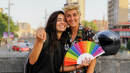 multiracial and queer couple with rainbow hand fan. human rights - obrazy, fototapety, plakaty