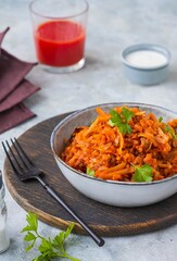 Lazy cabbage rolls, a thick stew of cabbage, carrots, rice and minced meat in a gray ceramic bowl on a gray concrete background.