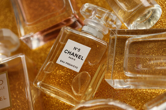 TERNOPIL, UKRAINE - SEPTEMBER 2, 2022 Chanel Number 5 Eau Premiere  worldwide famous french perfume bottle among other perfumes on shiny  glitter background in yellow colors Stock Photo
