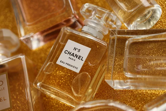TERNOPIL, UKRAINE - SEPTEMBER 2, 2022 Chanel Number 5 Eau Premiere  worldwide famous french perfume bottle among other perfumes on shiny  glitter background in yellow colors Photos
