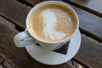 close up of white brown frothy foam in the hot cup of cappuccino. Softness of drink. Breakfast time in the morning at cafe. Coffee drink on wooden table, energy boost