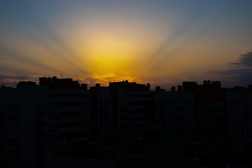 blur dark, beautiful orange sunset over the city, visible city line of buildings and houses, darkness and sunbeam in sky, early morning, sunrise 