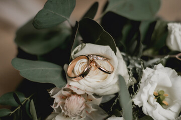 Two wedding rings and engagement ring on flower bouquet
