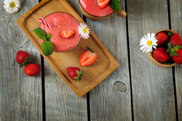 Fresh strawberry smoothie with strawberries on a background of wooden boards. High angle view, selective focus, daylight