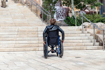 Woman or man with impaired mobility using wheelchair blocked from trying to get up the stairs to...