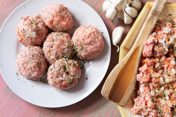 Albóndigas crudas e ingredientes con luz natural desde la ventana