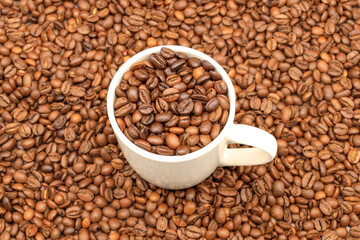 White cup filled with coffee beans on rustic wooden table. Top view. Coffee concept for cafes