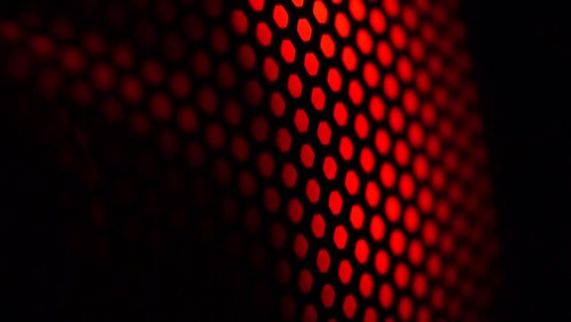 Colorful light of computer fan shines through the holes of protective grid. illumination glows in the dark. led lighting of gaming pc