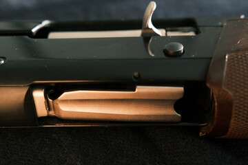 Closeup shotgun shutter. Hunting semi-automatic shotgun with wooden butt on dark background