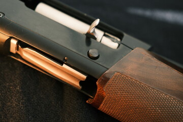 Closeup shotgun shutter. Hunting semi-automatic shotgun with wooden butt on dark background