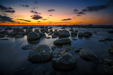 Obraz premium Wonderful orange sunset on the rocky coast of the sea
