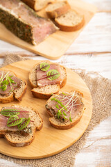 Bread sandwiches with jerky salted meat, sorrel and cilantro microgreen on white. side view, selective focus.