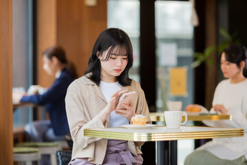 カフェでスマホを見る若い女性