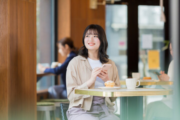 カフェでスマホを見る若い女性