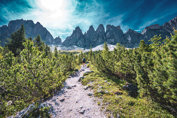 Athletic woman walks along beautiful hike trail at Seceda in the dolomites at noon. Seceda, Saint Ulrich, Dolomites, Belluno, Italy, Europe.