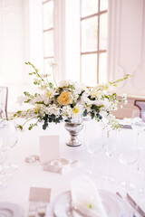 Festive table decorated with white flowers for seating guests at a wedding banquet. Vertical banner, selective focus