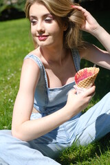 Girl in the blue jeans denim eating red ice cream