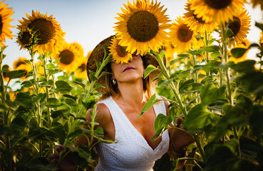 beautiful woman smelling the scent of nature in a field of sunflowers in el puerto de santa maria, andalusia spain. - obrazy, fototapety, plakaty