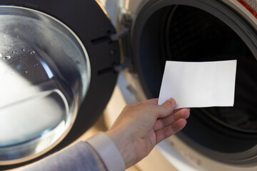 Woman putting a laudry sheet in the washing machine - obrazy, fototapety, plakaty
