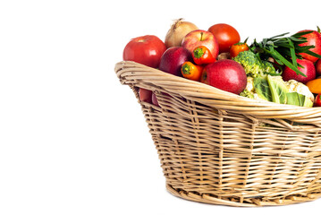 Assorted organic vegetables and fruits in wicker basket isolated on white background. Space for text.