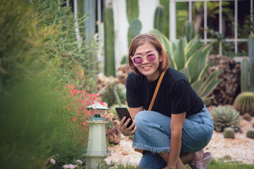 beautiful asian woman holding smart phone toothy smiling in home garden