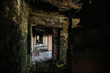 Fototapeta na wymiar Burnt building interior. Ruined coridor walls in black soot. Consequences of fire