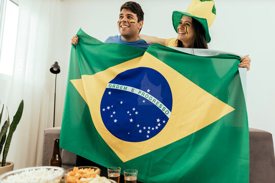 Football fans friends watching Brazil national team in live soccer match on TV at home