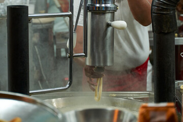 Detail of male hand operating churro making machine at funfair food truck