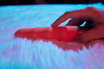 desire concept : Woman lying in bed holding a dildo vibrator in her hand to help herself.