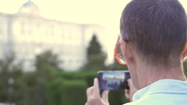 Senior male taking picture with smartphone of Madrid Royal Palace