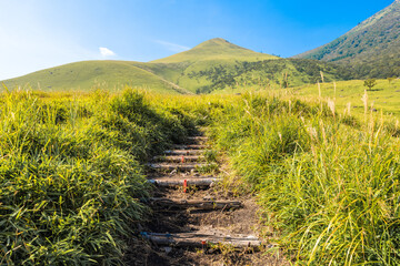 Dramatic view of high mountains and green field with stairs way under the blue sky, Mt. Yufudake in Oita Prefecture in Japan, Travel or outdoor background
