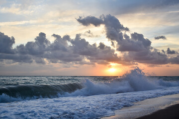 Beautiful sunset scene on a beach with sea, waves and clouds