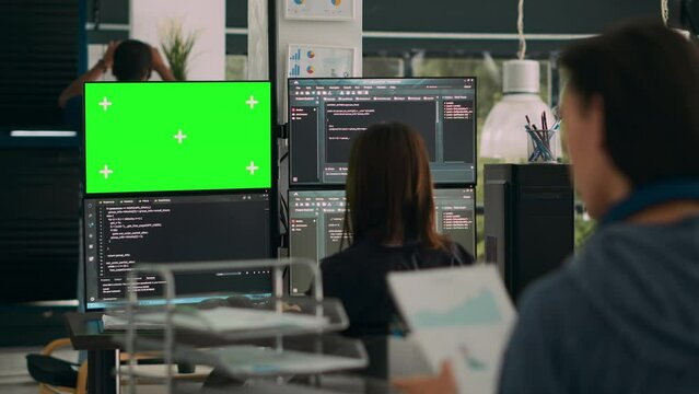 Woman programer looking at greenscreen and code on terminal window, working with chromakey display and html script in it office. Using isolated mockup copyspace on software development. Tripod shot.